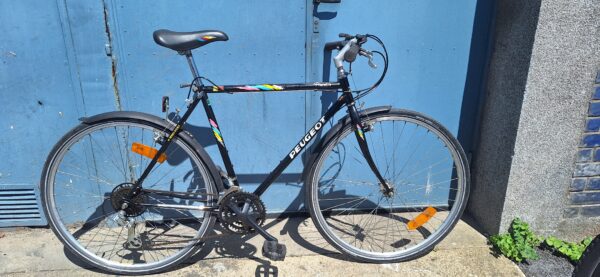 Vtt rigide Peugeot Princeton 18 vitesses, roues de 28 pouces, équipé en pneu profil route.  Gardes boues
